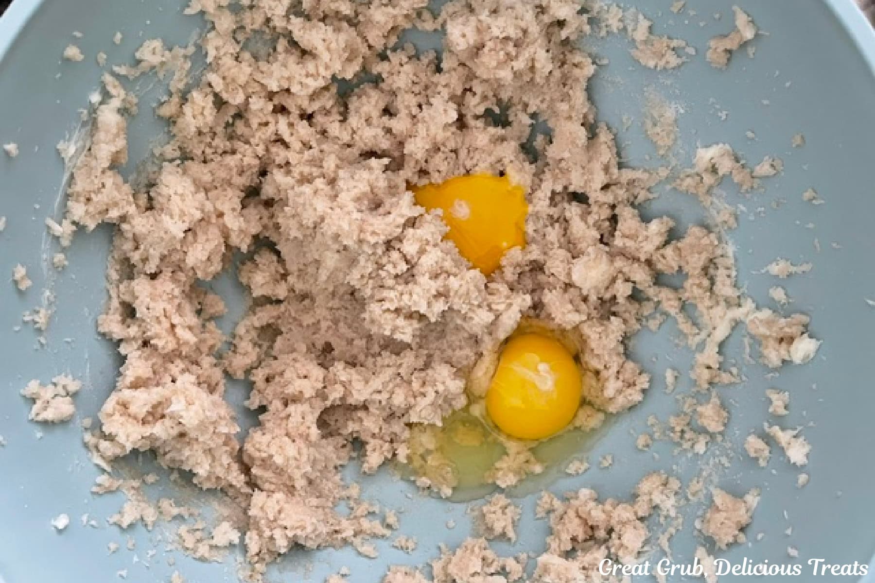 A light blue mixing bowl with the wet cookie batter ingredients in it.