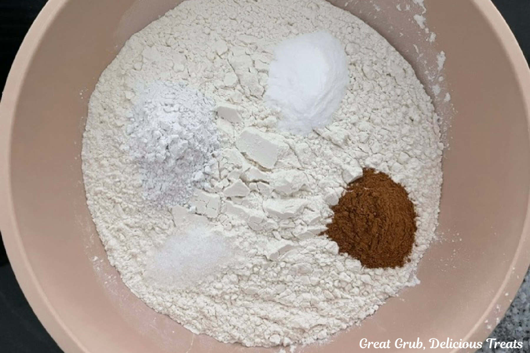 A tan mixing bowl with the dry cookie batter ingredients in it.