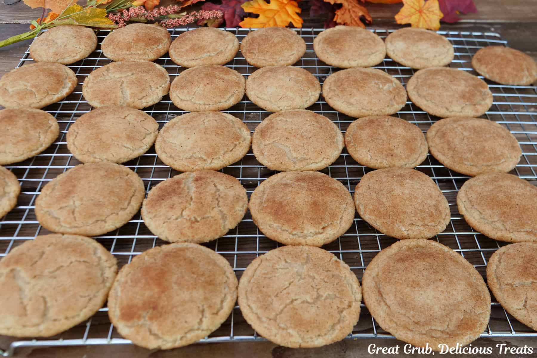 A wire rack with thirty one pumpkin spice snickerdoodles on it.