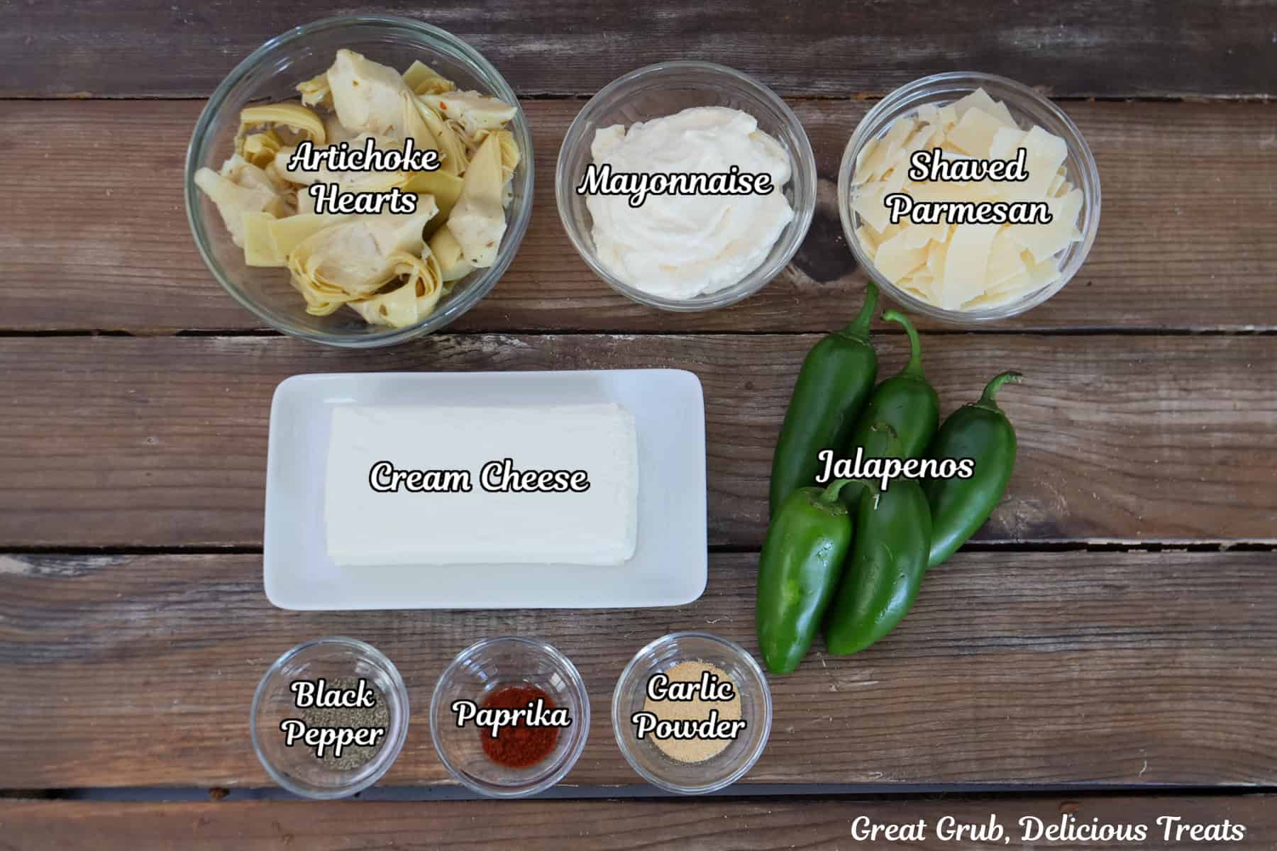 A rustic wood surface with all the ingredients placed on it to make roasted jalapeno artichoke dip.