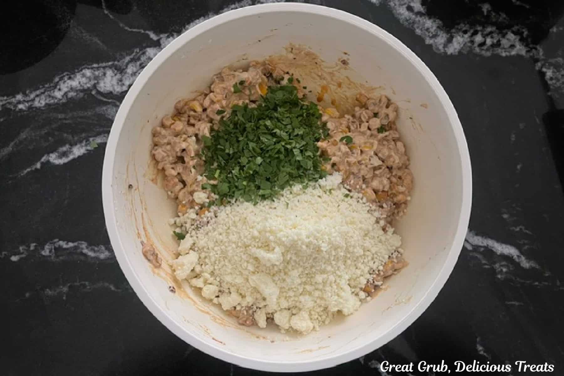 a white mixing bowl with all the ingredients for street corn dip in it before being mixed together.